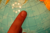 Mapa del mundo señalado por un dedo índice.