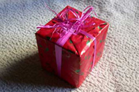 Paquete envuelto en papel de regalo rojo y con una cinta rosa.