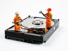 Imagen en la que se ven dos muñecos en acción de trabajar encima de un disco duro.