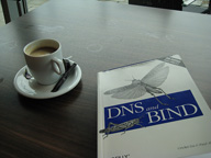 Foto de un libro con el título DNS BIND encima de una mesa junto a una taza de café.