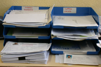 Foto de varias bandejas clasificadoras de documentos, llenas de papeles, sobre una mesa.