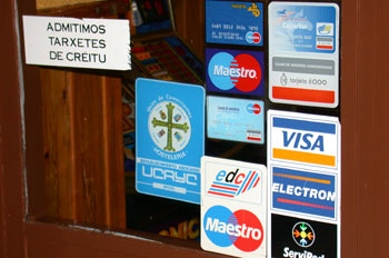 Foto de la entrada de un comercio en el que aparece un cartel que dice que se admiten tarjetas de crédito, junto a los logotipos de las tarjetas que se admiten.