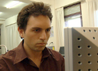 Imagen que muestra el rostro de un hombre sentado frente a la pantalla de un ordenador.
