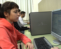 Imagen que muestra a una chica sentada, trabajando con un ordenador.