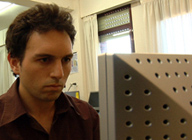 Imagen que muestra a un hombre sentado, mirando la pantalla de un ordenador.