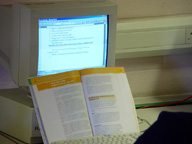 Pantalla de un ordenador con un libro abierto en primer plano.