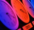 Tres relojes marcando la hora en distintos países con reflejos rojizos y azules.