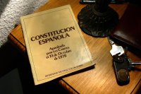 Imagen que muestra un libro de la constitución española encima de una mesa.