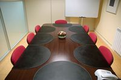 Imagen en perspectiva de una mesa de reuniones con las sillas vacías.