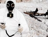 Hombre vestido con máscara y traje protector de radiaciones  midiendo niveles radiactivos en la nieve.