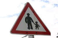 Señal de aviso de peligro de abuelos paseando con sus nietos.