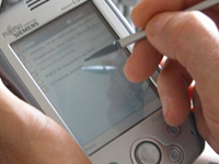 Una mano está escribiendo sobre una PDA