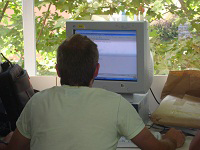 Se ve un chico de espaldas trabajando con un ordenador.