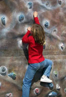 Una niña con el pelo castaño , viste pantalón vaquero azul y jersey rojo. 