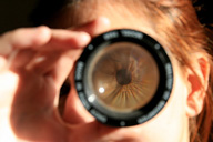 Persona mirando un caleidoscopio, de forma  que se ve la pupila y el iris ampliados como si fuera una lupa. 