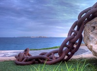 Una cadena al frente con el mar y una isla al fondo.