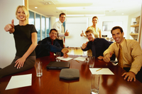 Un grupo de trabajadores en torno a una mesa de reuniones en una oficina, muestran su aprobación con el pulgar hacia arriba. Hay cuatro hombres y dos mujeres. 