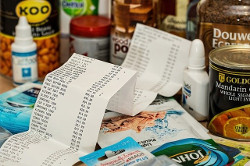 Imagen en la que se muestra un ticket, con multitud de líneas de ticket, rodeado de muchos productos.