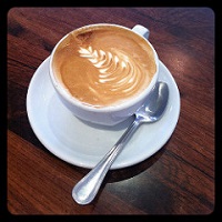 Imagen de primer plano de una taza de café sobre un plato y un fondo de mesa de madera marrón oscuranegro.