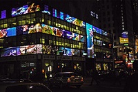 Fotografía nocturna de un edificio con un montón de monitores mostrando diferentes cosas.