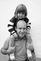 Fotografía de un padre con su hija encima de los hombros.