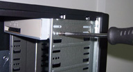 Vista lateral de la caja del ordenador en su parte superior donde se están apretando los tornillos que fijan el DVD al chasis. 