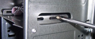 Vista lateral de la caja del ordenador en su parte central donde se están apretando los tornillos que fijan el lector de tarjetas al chasis.