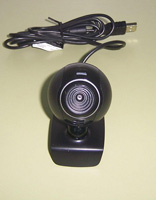 Pequeña cámara web con pinza para su sujeción y su cable acabado en un conector USB. Tiene un pequeño micrófono incorporado.